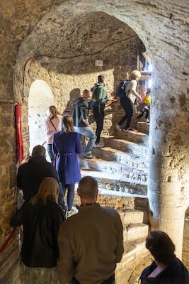 A group of people walk up a stone spiral staircase